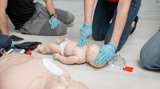 Several people engaged in CPR training, demonstrating techniques on a medical mannequin in a professional environment.