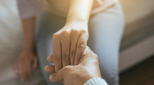 A pair of people holding hands in a comforting gesture.