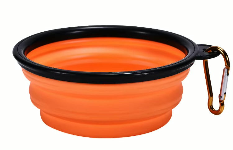 Orange silicone travel bowl with black rim and carabiner on a white background