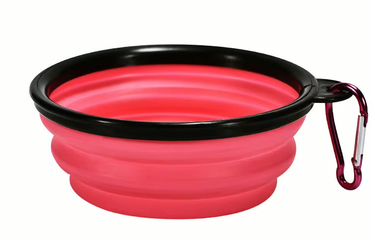 Pink silicone travel bowl with black rim and carabiner on a white background