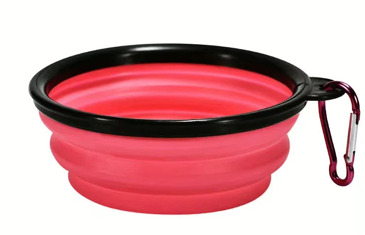 Pink silicone travel bowl with black rim and carabiner on a white background