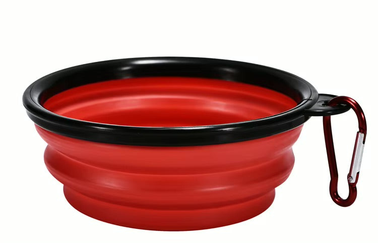 Red silicone travel bowl with black rim and carabiner on a white background