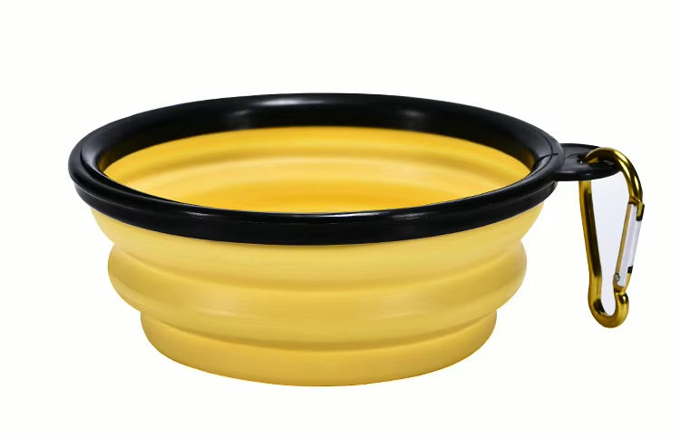 Yellow silicone travel bowl with black rim and gold carabiner on a white background