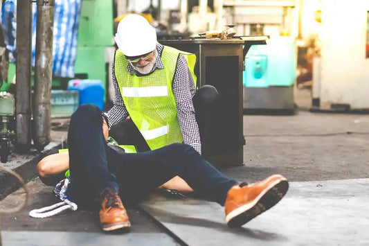 A man in a safety vest is lying on the ground, indicating a possible safety incident or emergency situation.
