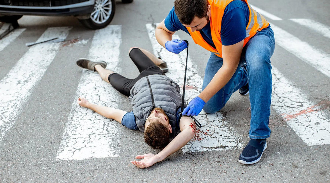 A person aiding a man with medical care near an ambulance.