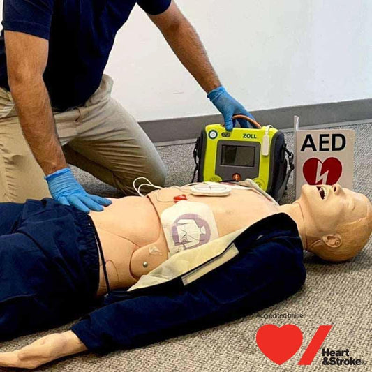 Person with a AED demonstrating how to use it on a manikin.